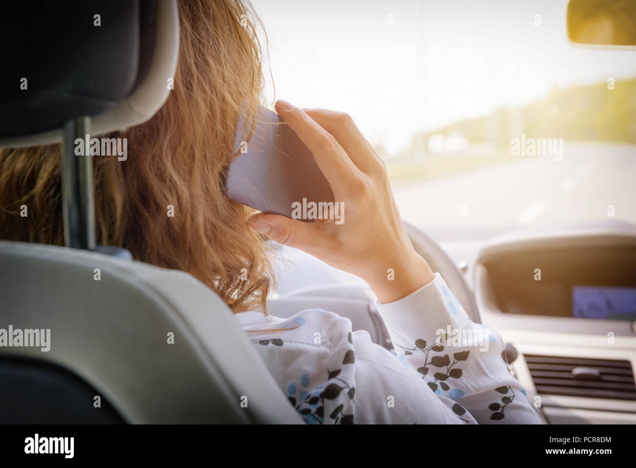 Donna che utilizza il telefono mentre si guida la macchina. Rischiosi comportamenti di guida concept Foto Stock