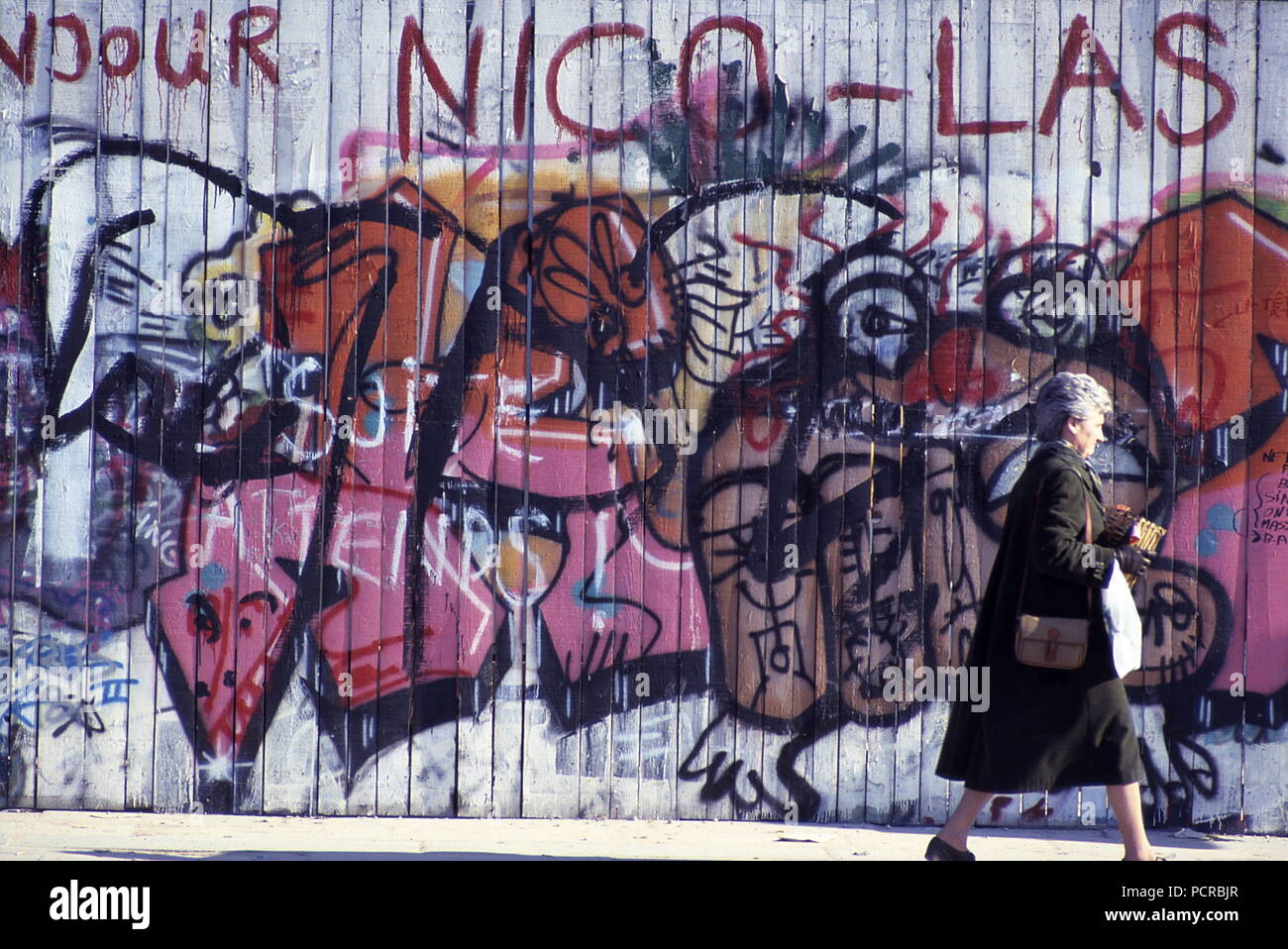 AJAXNETPHOTO. 1985. Parigi, Francia. - Arte dei graffiti - donna cammina passato GRAFITTI immagini dipinte su un sito in costruzione tavolato in legno palizzata nel centro della citta'. Foto:JONATHAN EASTLAND/AJAX REF:891391 Foto Stock