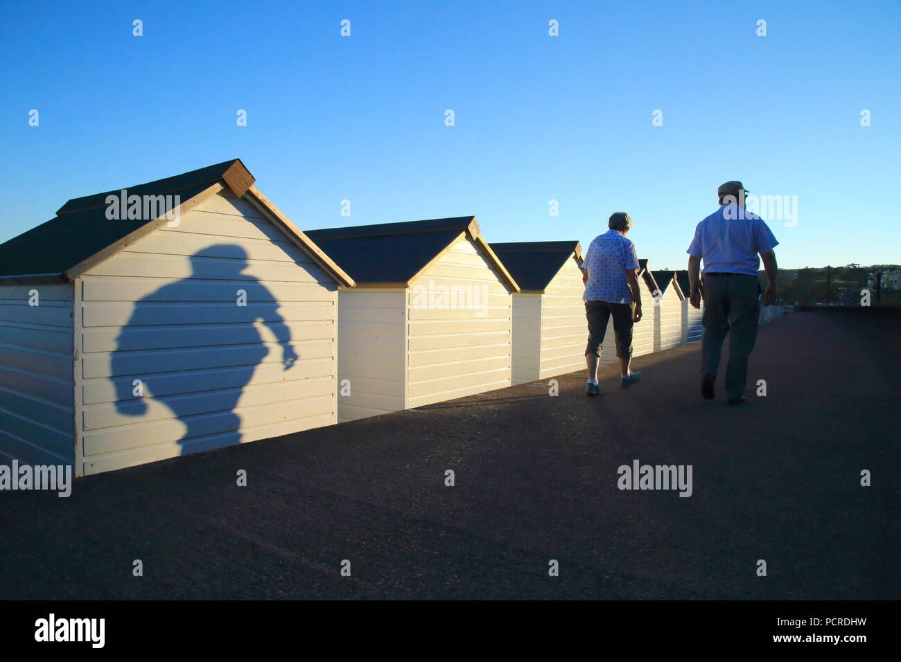 Le ombre delle persone che passano dalla spiaggia bianca di capanne in città costiera di Seaton in East Devon Foto Stock