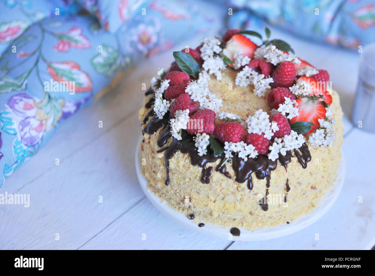 torta al miele, decorata con frutti di bosco e cioccolato. dolce cena familiare. torta di vacanza. colazione sul balcone. Foto Stock