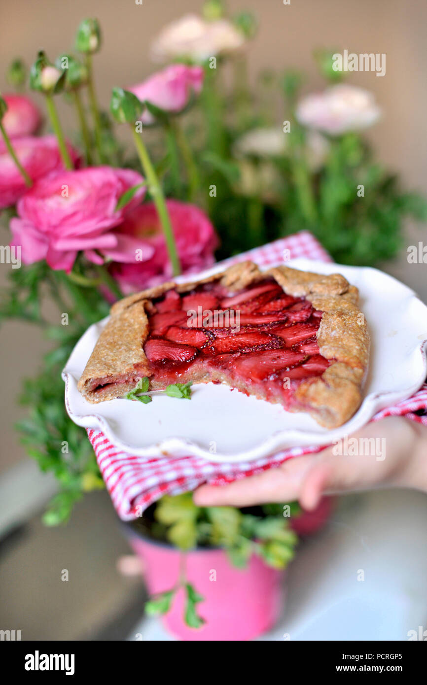torta aperta con fragole. in penne per bambini. decorazione del balcone con fiori freschi. fiori rosa. Foto Stock