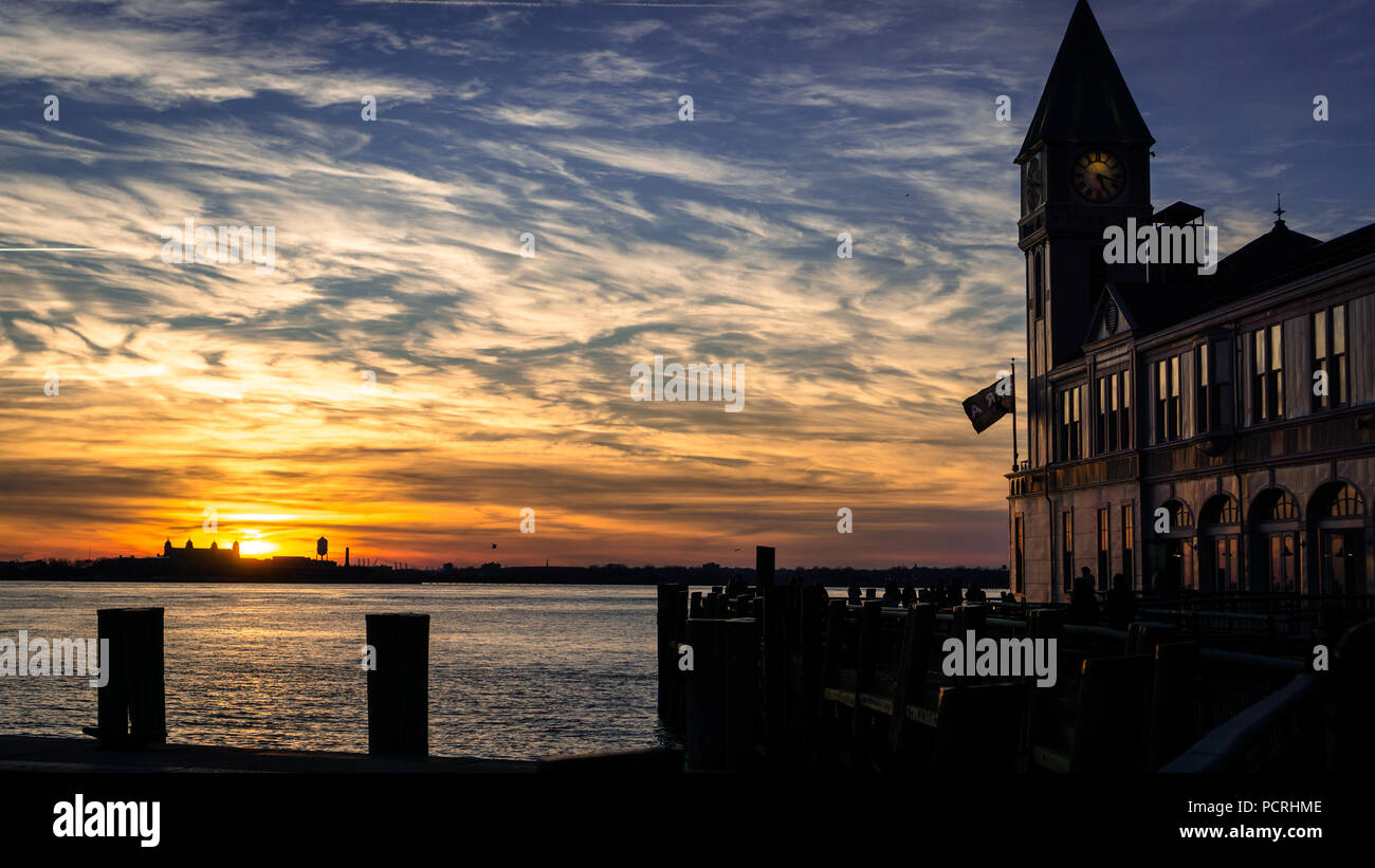 Punto di riferimento Pier A su una bella notte invernale leggermente riflettendo il sole da un tramonto in inverno, incandescente attraverso il Fiume Hudon, NYC, Stati Uniti d'America. Foto Stock