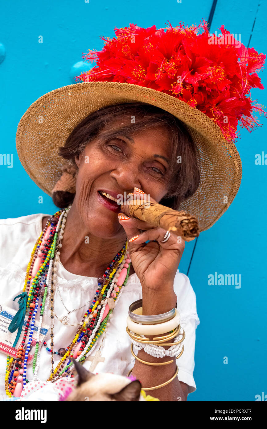 Vecchia donna cubana fuma un sigaro cubano sulla strada e pone con il suo gatto per i turisti, La Habana, Cuba, Caraibi, America centrale, La Habana, Cuba Foto Stock