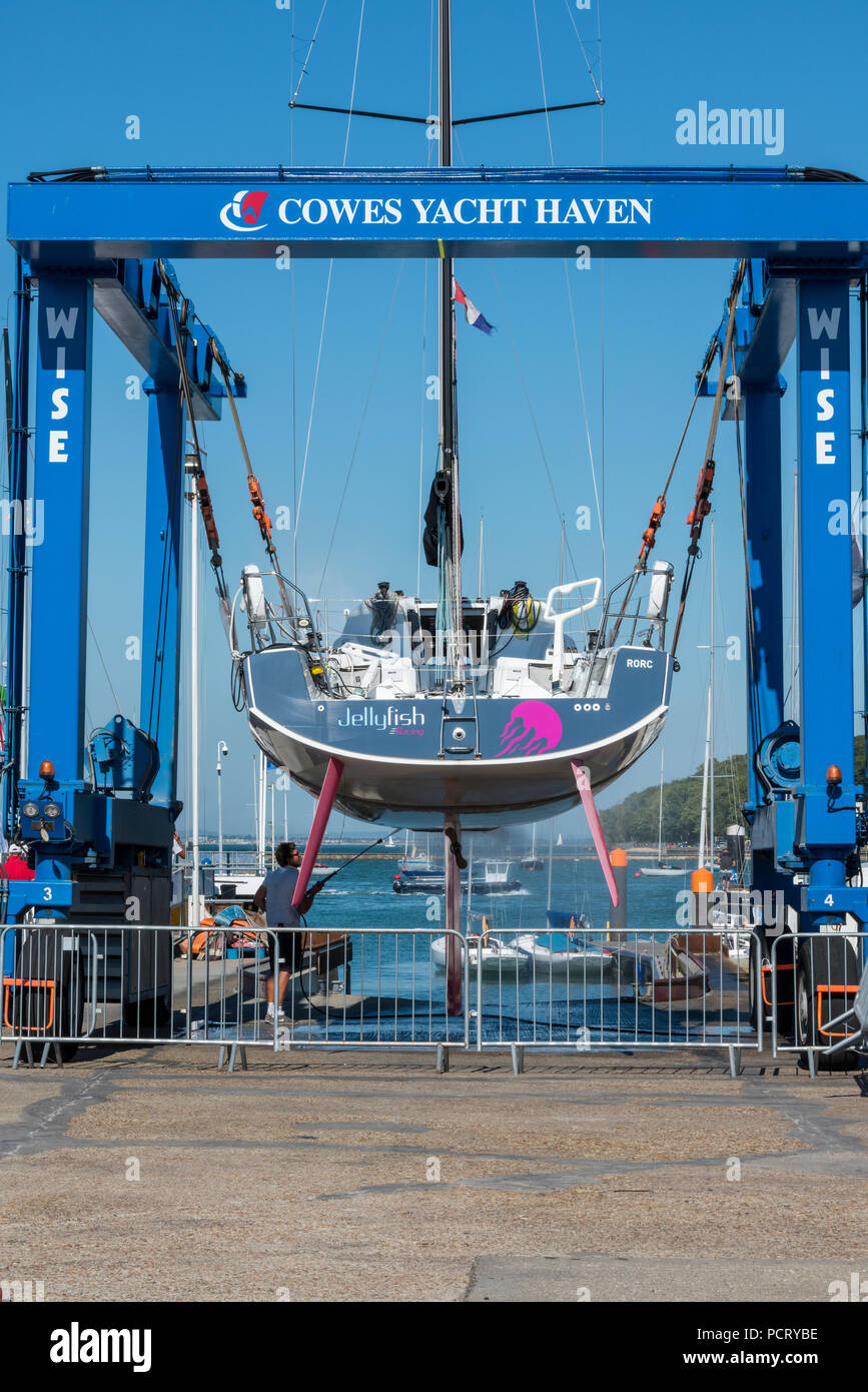 Un grande yacht da corsa che viene sollevato fuori dall'acqua a Cowes yacht haven on the Isle of Wight utilizzando un paranco in barca nella marina. Foto Stock