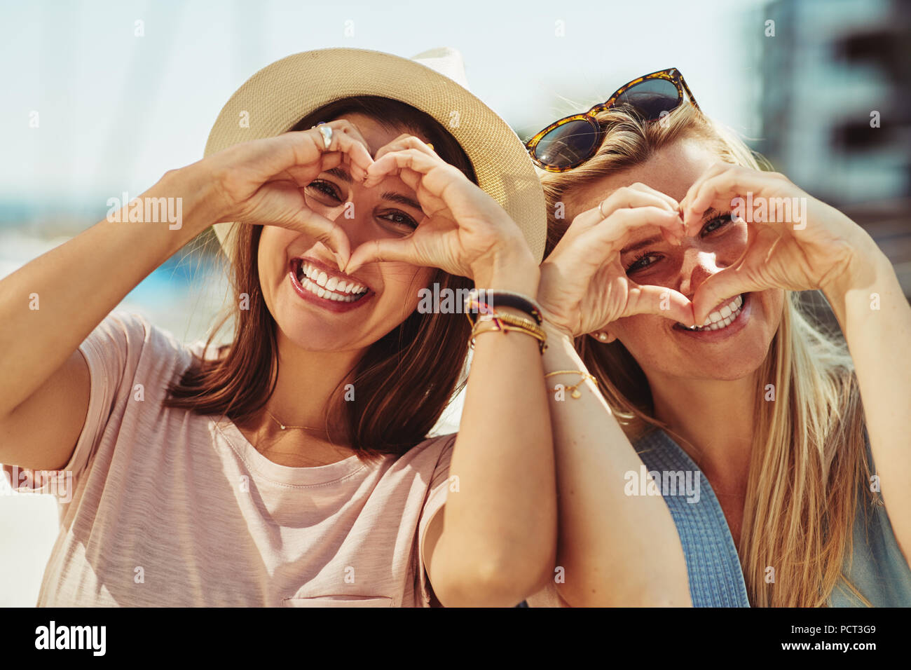 Sorridente due giovani amici facendo cuore forme con le loro mani mentre avente una bella giornata di divertimento insieme in estate Foto Stock