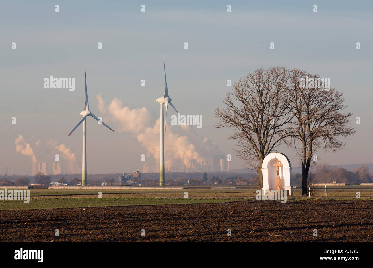 Von zwei Linden flankierter Bildstock aus dem 18. Jahrhundert, dahinter zwei Windkraftanlagen und Kohlekraftwerke (Rheinisches Braunkohlerevier) Foto Stock