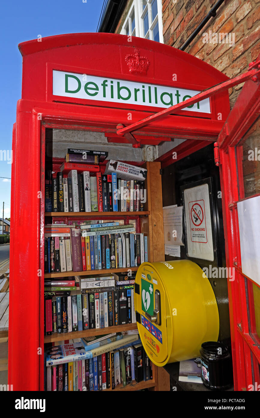 Hatton village K6 telefono rosso scatola, utilizzato come defibrillatore e prenota lending library, Hatton Lane, Warrington, Cheshire, North West England, Regno Unito, WA4 4D Foto Stock