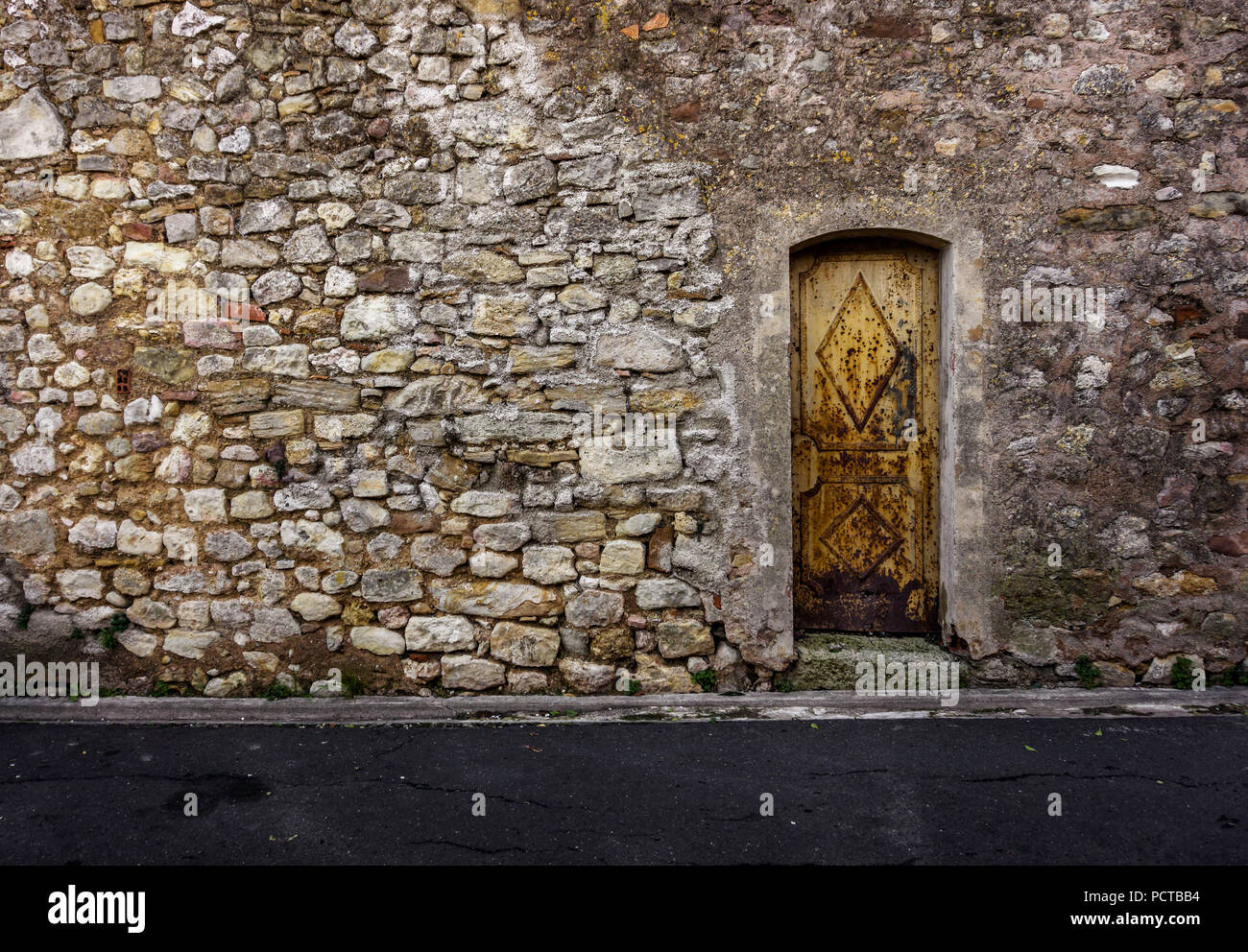 Muro di pietra con porta di ferro in Quarante Foto stock - Alamy