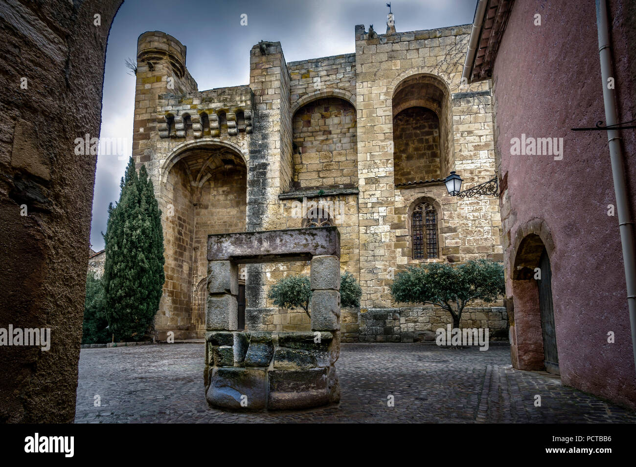 Cruzy, Place de l'Église, Chiesa di Église Sainte Eulalie de Mérida fu costruito in epoca romana - stile gotico tra il X e il XIV secolo, di fronte ad essa una vecchia fontana di pietra Foto Stock