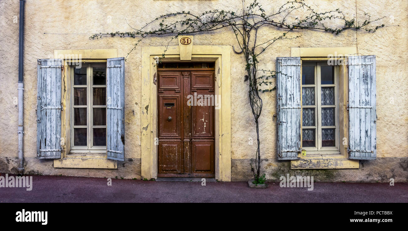 La facciata della casa in Coursan, porta di legno, impianti, finestra e persiane Foto Stock