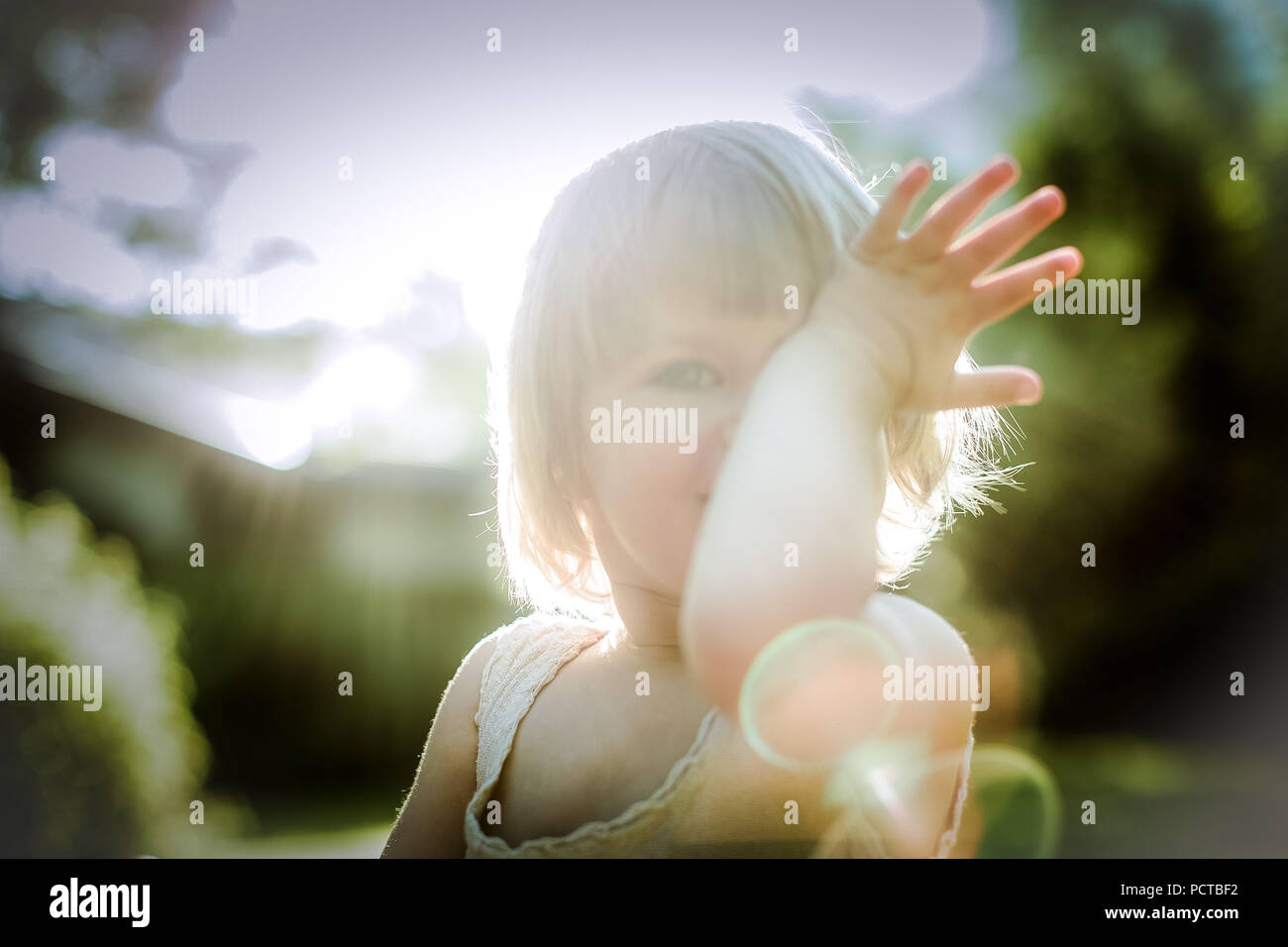Bambino, ragazza bionda circa 3 anni, tenendo la mano davanti al suo volto Foto Stock