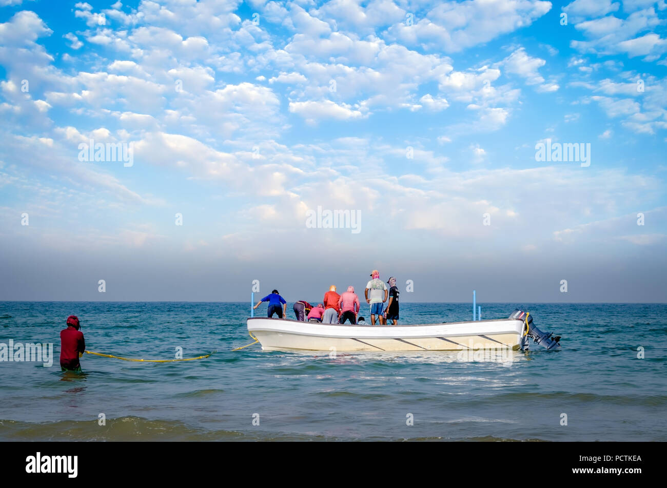 Gruppo di pescatori cercando di trascinare la rete piena di pesci alla barca, mentre uno tiene la corda per non consentire la barca ad allontanarsi. Foto Stock