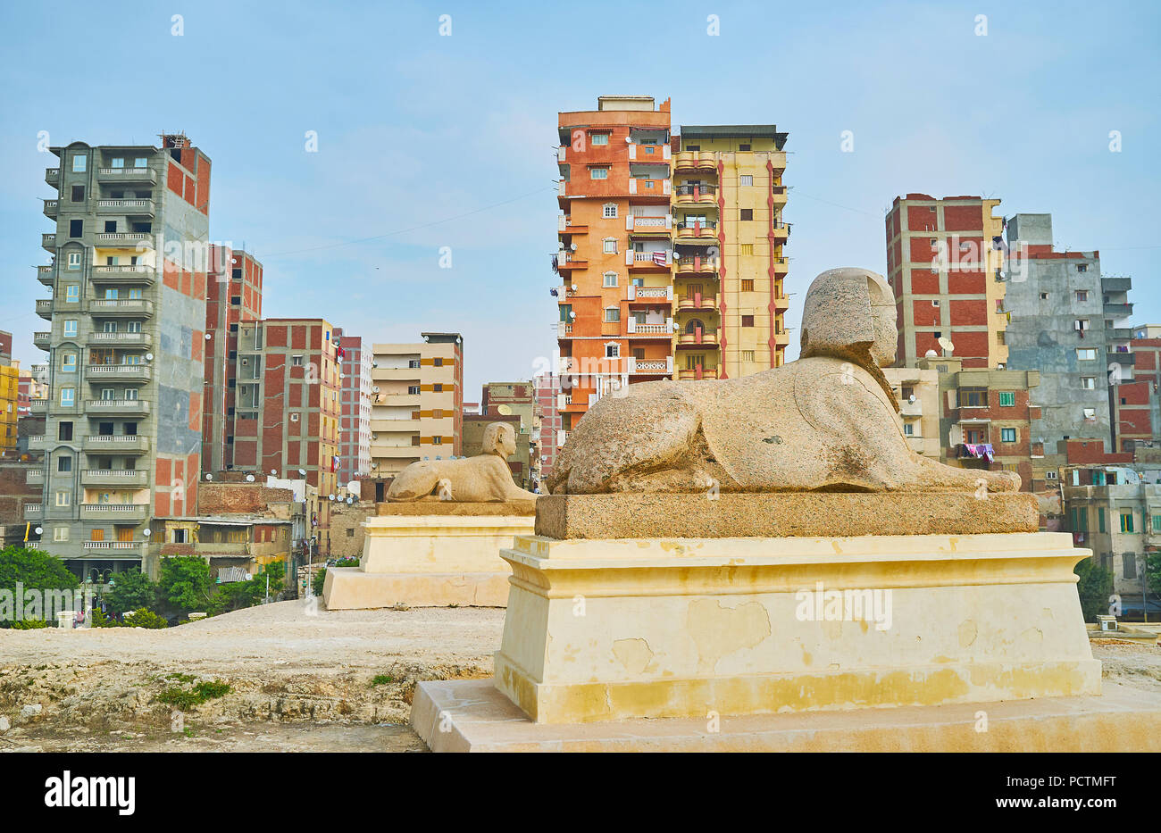 La scena urbana con due statue di sfingi in primo piano, Amoud Sawari al sito archeologico, Alessandria, Egitto. Foto Stock