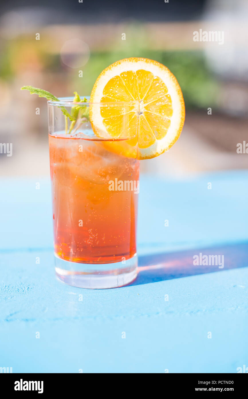 Bicchiere di aperol spritz con la menta e una fetta di arancia in una giornata di sole. Foto Stock