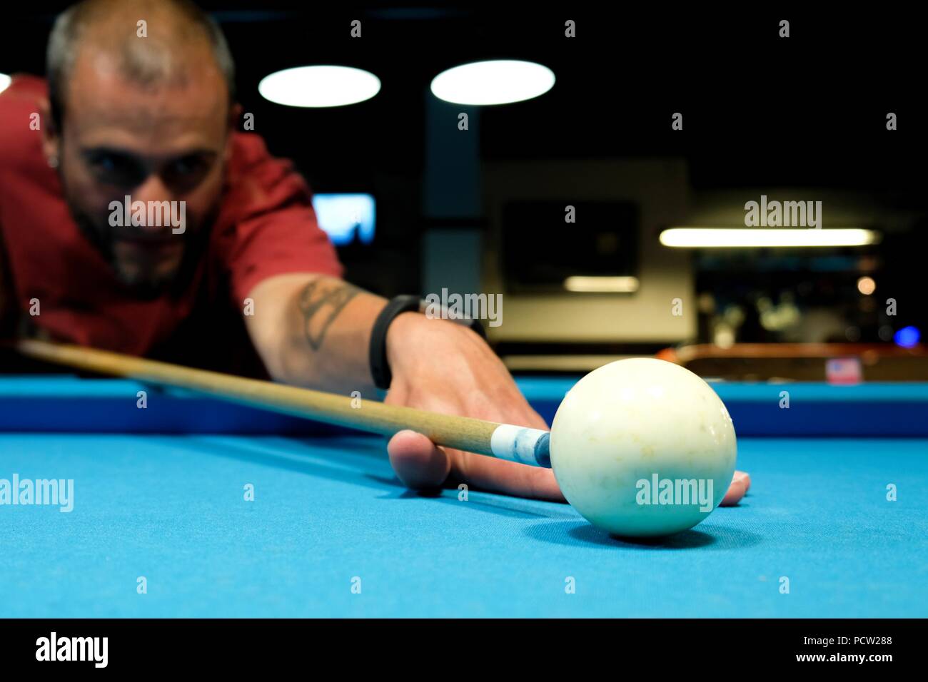 Un giocatore del pool di linee con fiducia fino dietro la bilia battente di prenderci di mira, focalizzata sul punto di contatto Foto Stock