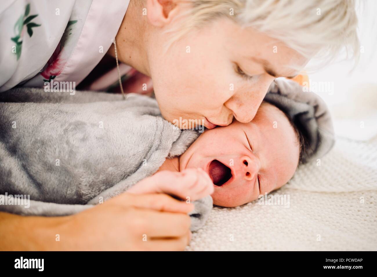 Madre bacia sbadigli o piangere neonato boy Foto Stock