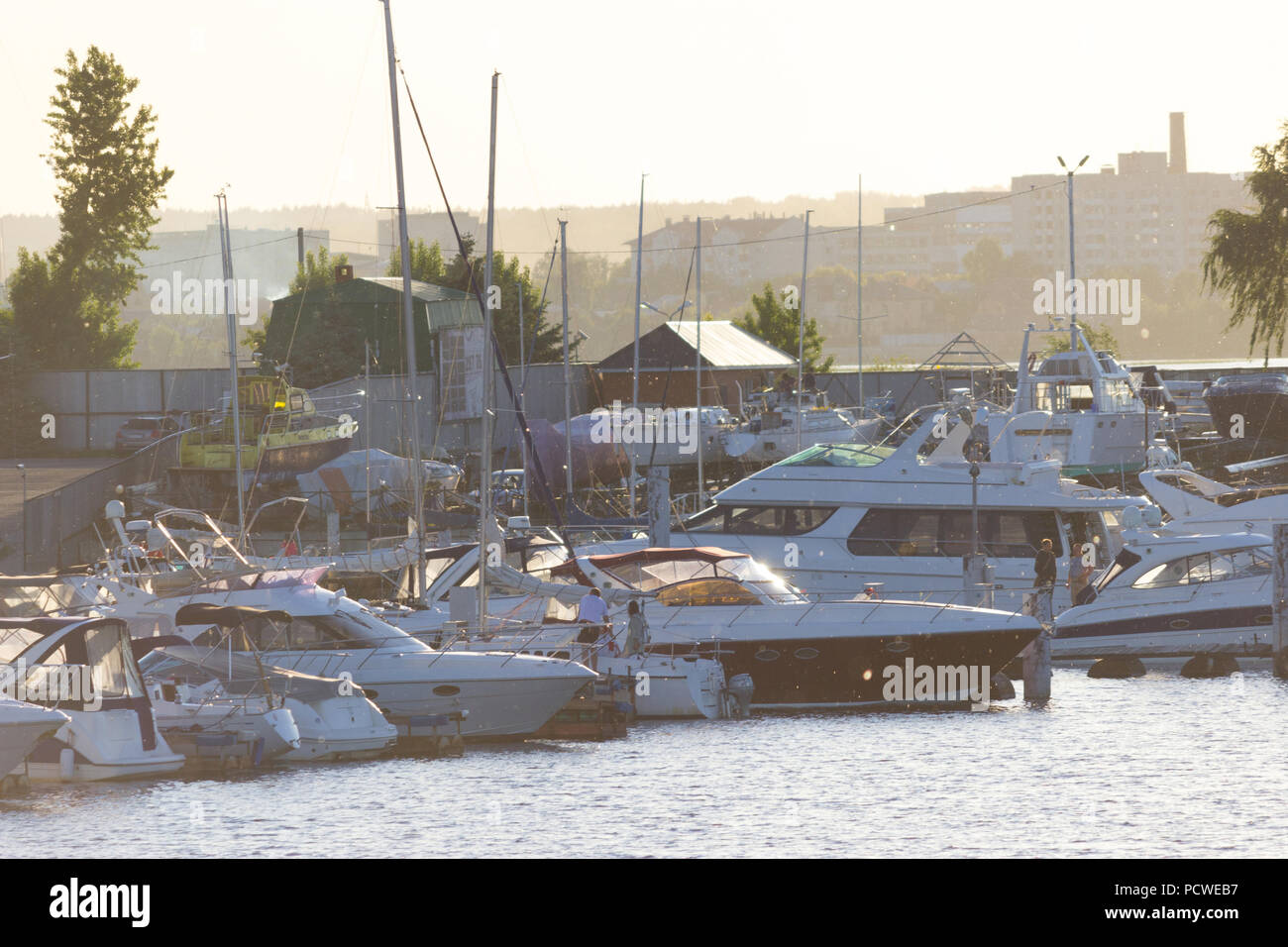 Marine con motore e barche a vela in luce del tramonto Foto Stock