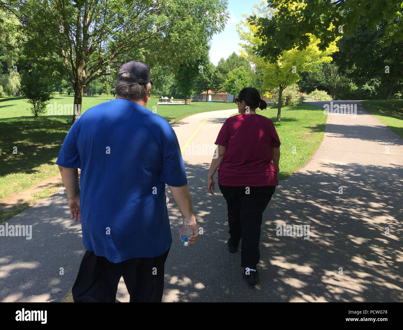 Due set di pesanti gli individui su una passeggiata in un grande parco pubblico, Ontario, Canada Foto Stock