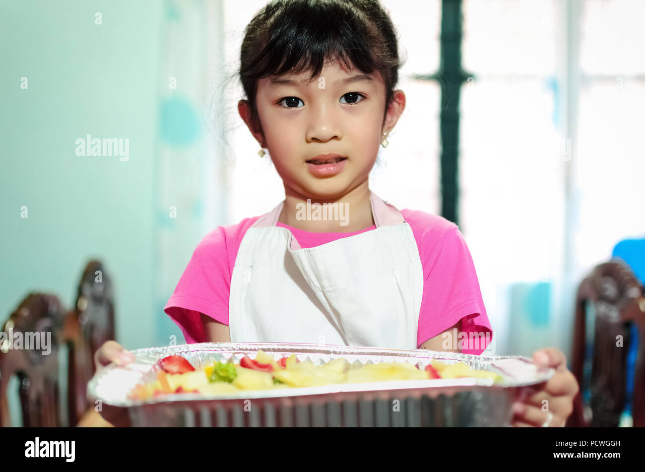 Una giovane ragazza che serve misti insalata di frutta che lei ha preparato. Foto Stock