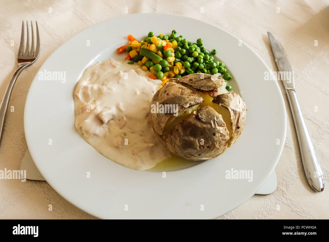 Un pasto a base di patate al forno con pollo in salsa bianca e verdure miste. Foto Stock