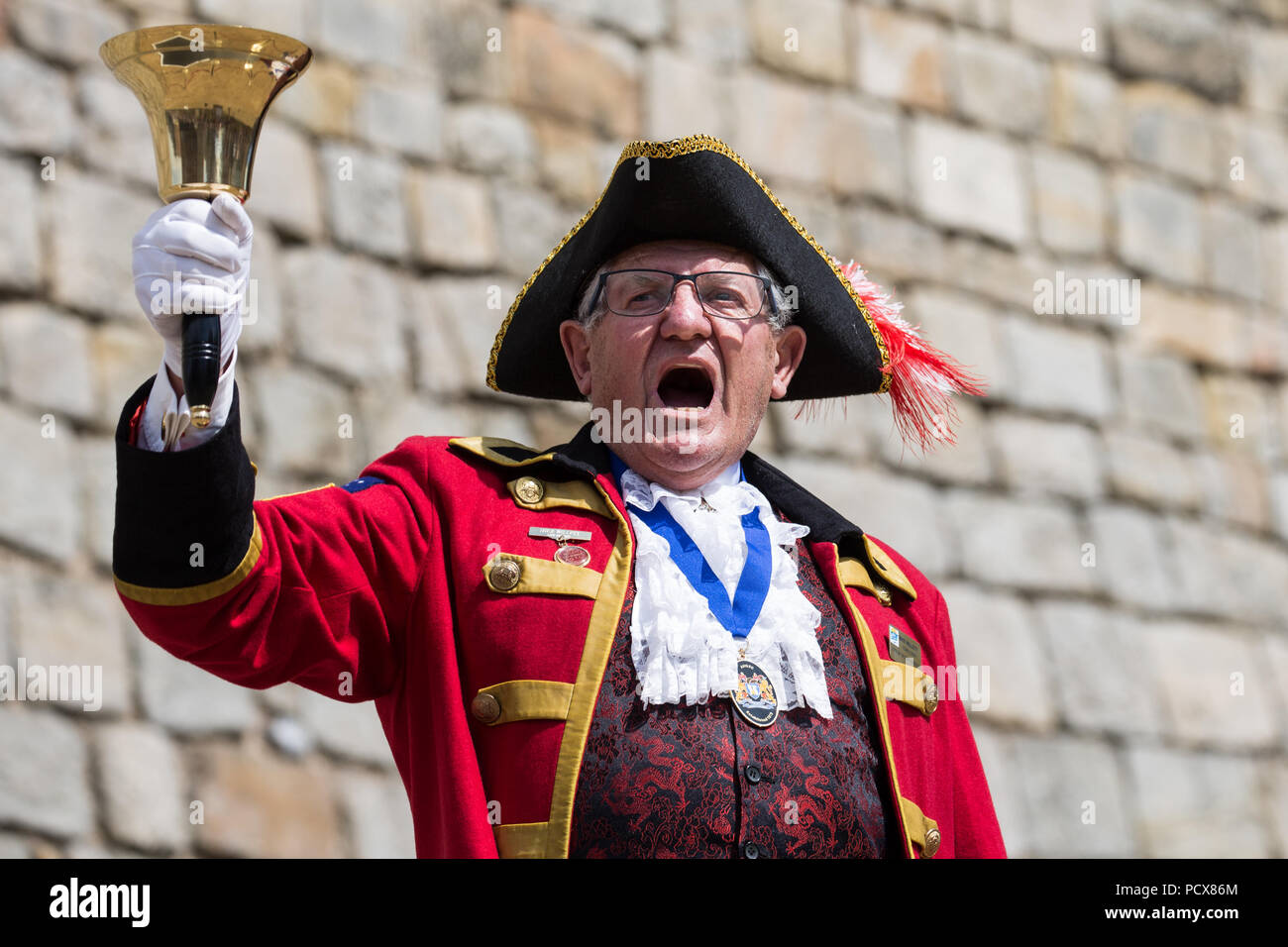 Windsor, Regno Unito. 4° agosto 2018. Mike Willett, Town Crier di Victor Harbor in Sud Australia, prende parte alla antica e onorevole Guild of Town Criers (AHGTC) Campionato Nazionale sotto le mura del Castello di Windsor. Quaranta città criers da tutto il Regno Unito e due da Australia competere in due turni di pianto, il primo un grido iniziale segnato sulla dizione, flesso, la chiarezza e il volume e la seconda un grido sul tema di "Una celebrazione". Credito: Mark Kerrison/Alamy Live News Foto Stock