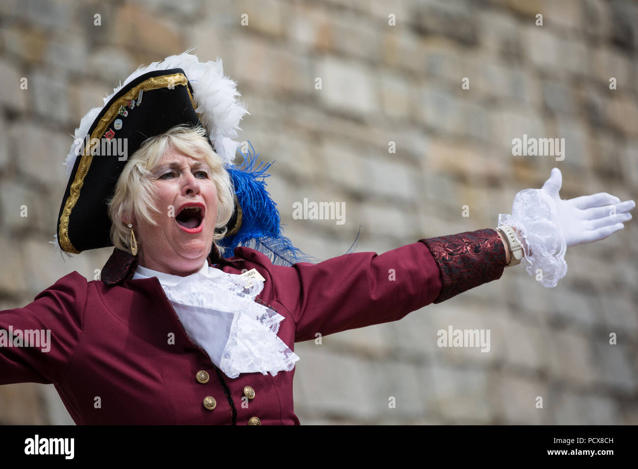 Windsor, Regno Unito. 4° agosto 2018. Jackie Edwards, Town Crier di Kingsteignton, prende parte alla antica e onorevole Guild of Town Criers (AHGTC) Campionato Nazionale sotto le mura del Castello di Windsor. Quaranta città criers da tutto il Regno Unito e due da Australia competere in due turni di pianto, il primo un grido iniziale segnato sulla dizione, flesso, la chiarezza e il volume e la seconda un grido sul tema di "Una celebrazione". Credito: Mark Kerrison/Alamy Live News Foto Stock