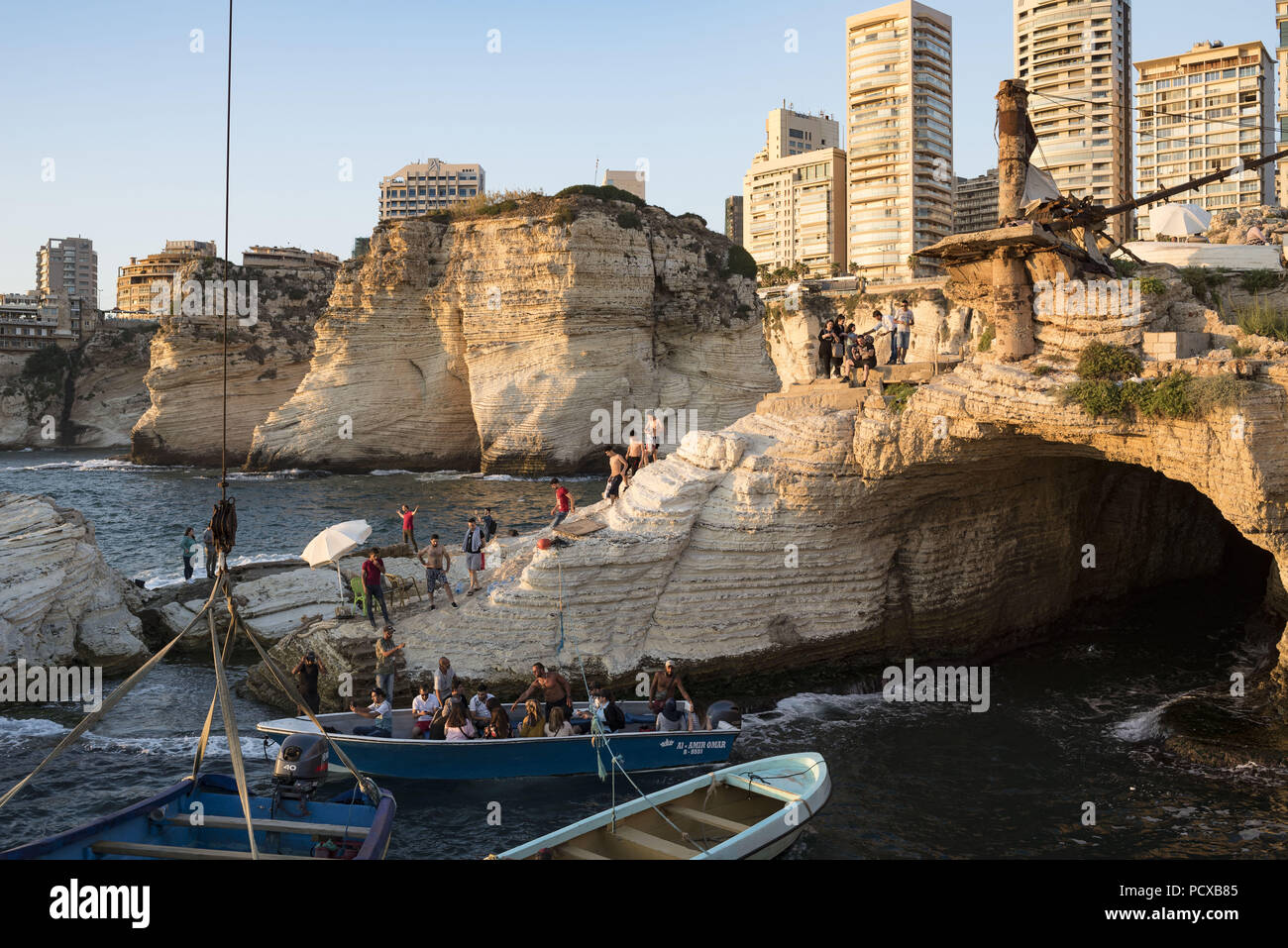 Beirut, Libano. 12 Luglio, 2018. La gente si vede in una barca e in piedi su una roccia al litorale.Beirut potrebbe presto essere la capitale solo sulla costa mediterranea che non dispone di una spiaggia pubblica. La capitale della costa è stata sviluppata in spiaggia privata club e resorts. A pochi anni fa la costruzione ebbe inizio nel Dalieh troppo, questo usato per essere un posto per picnic sulle sue colline, nuoto nelle sue piscine e per i pescatori per fare una vita. Credito: Antoine Abou-Diwan SOPA/images/ZUMA filo/Alamy Live News Foto Stock