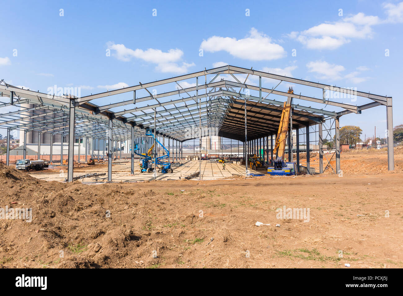 La nuova fabbrica grande magazzino costruzione di travi in acciaio telai assemblati a metà strada per il completamento. Foto Stock