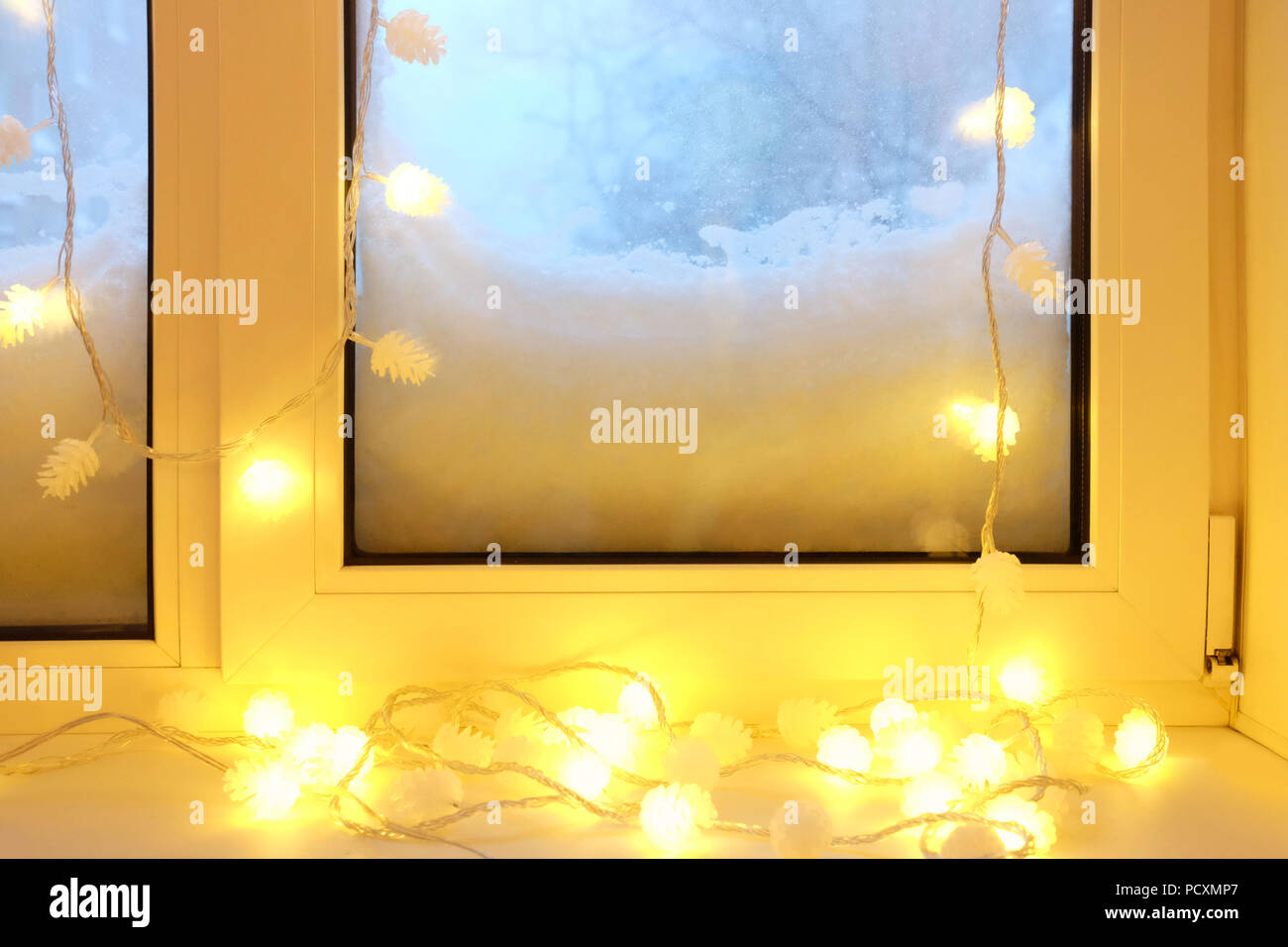 Ghirlanda elettrica sul davanzale a nevoso inverno sera Foto Stock