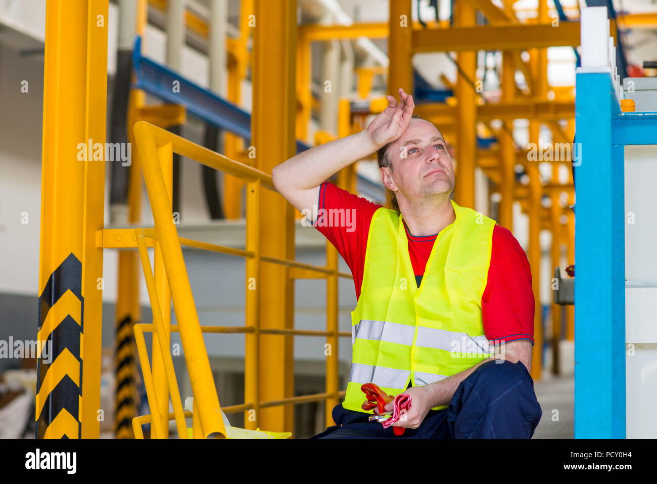 Stanco operaio di fabbrica strofinare il suo sudore e il riposo dopo una giornata di duro lavoro Foto Stock