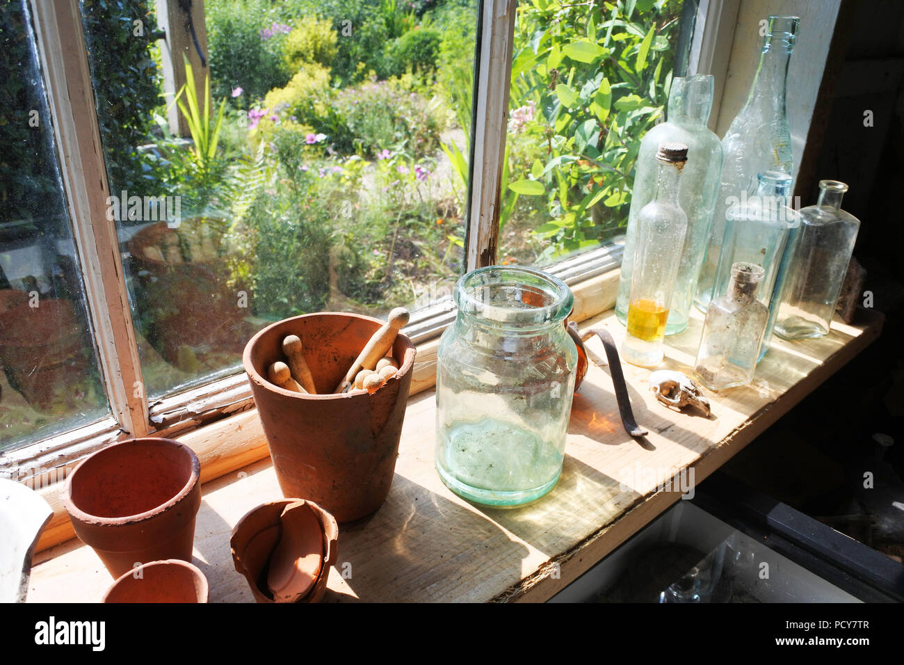 Bottiglie, vasetti di vetro e mollette nella finestra di un vecchio capanno da giardino, England, Regno Unito - Giovanni Gollop Foto Stock