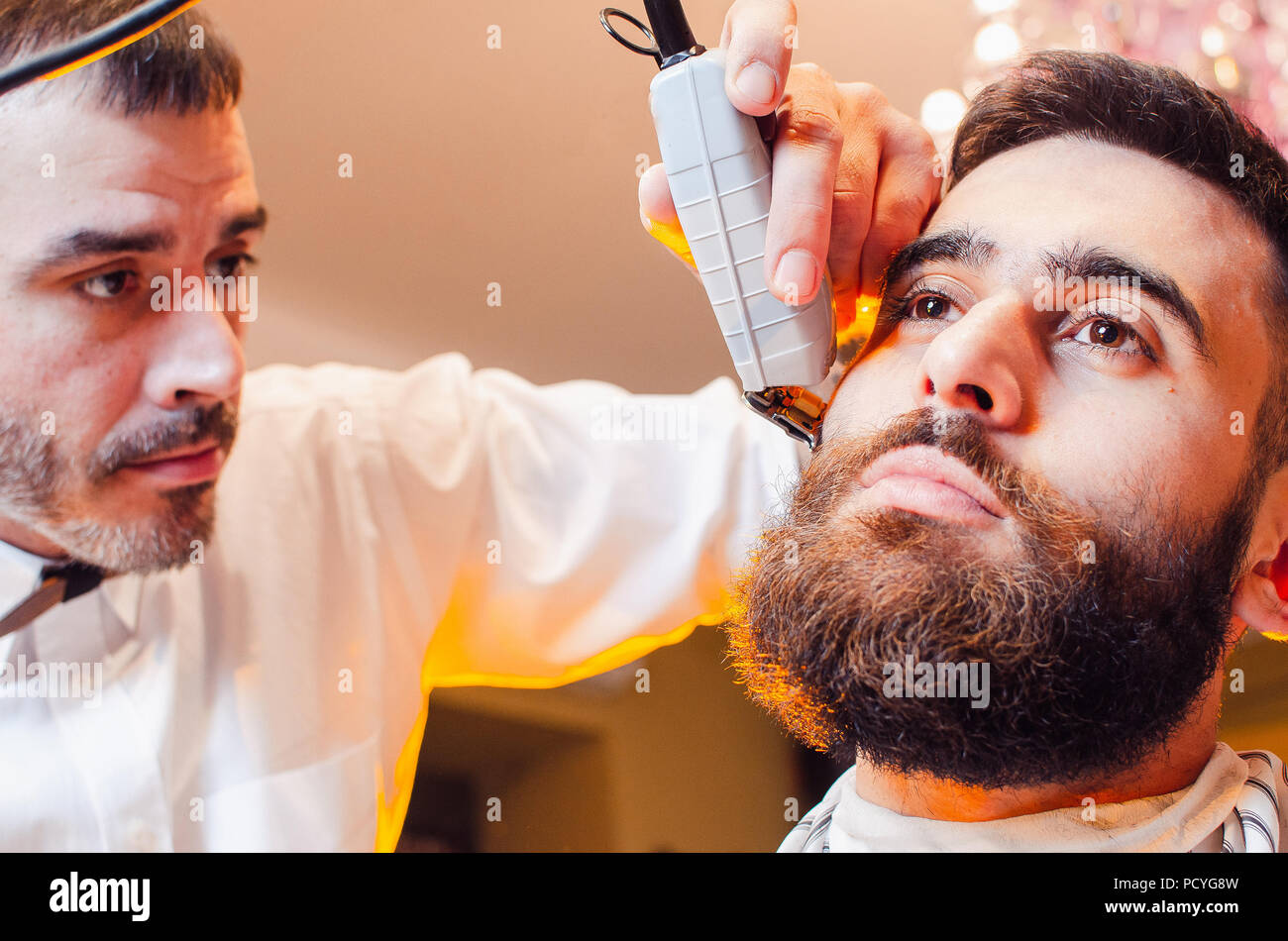 Barbiere tagli la barba con il rifinitore di precisione per un giovane  ragazzo bello con un baffi. Taglio di capelli di una barba a un maschio di  barbiere Foto stock - Alamy