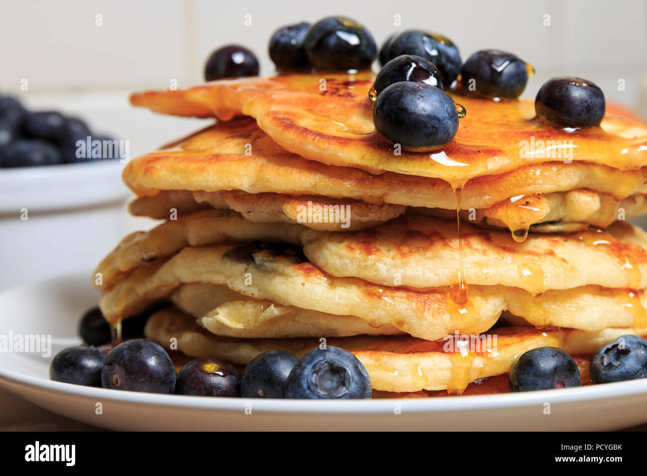 Una pila di stile americano e frittelle di mirtillo, con mirtilli e spruzzata con sciroppo Foto Stock