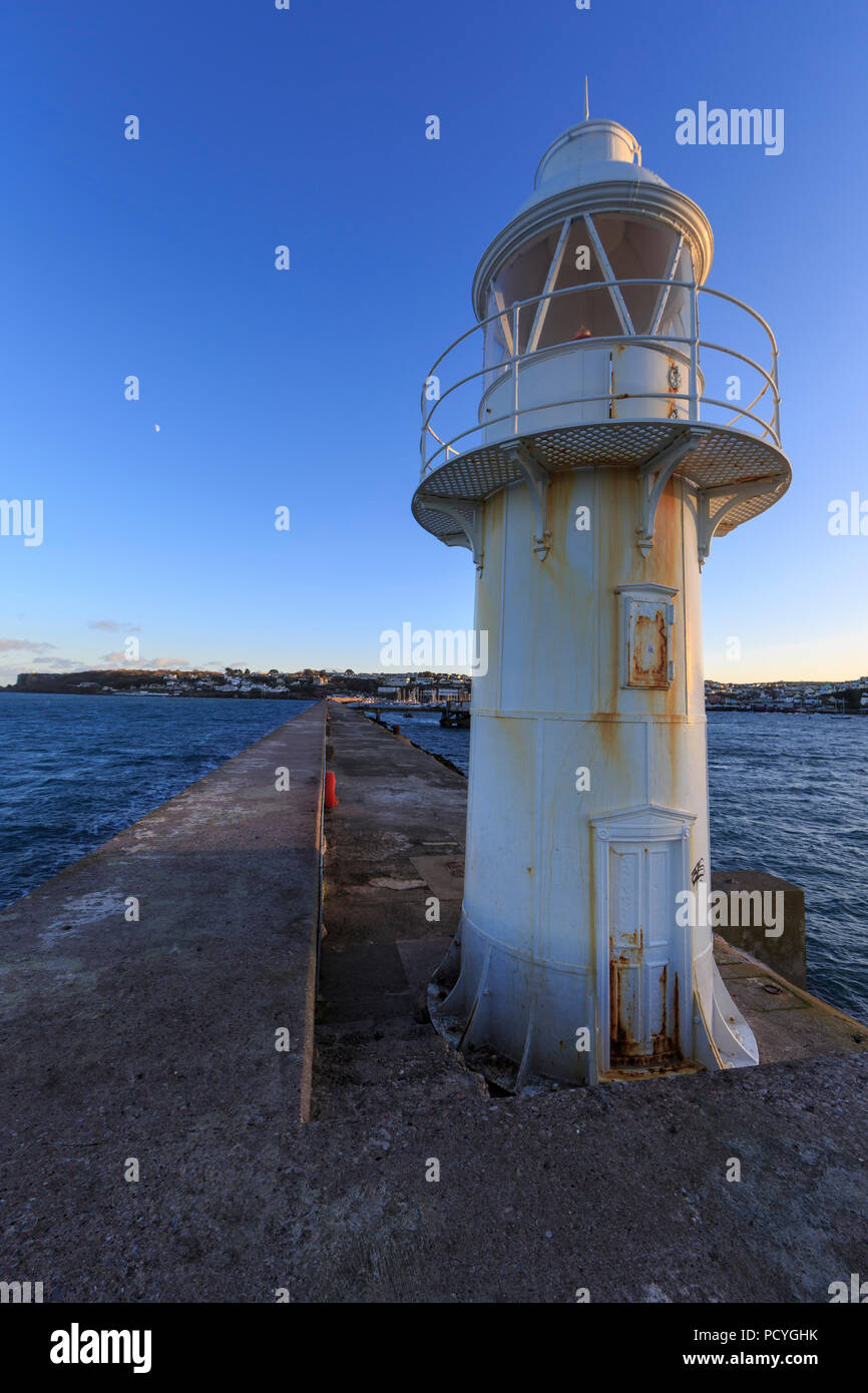 Un piccolo faro bianco sulla fine del frangiflutti a Brixham Harbour, brixham devon, si staglia contro un cielo blu chiaro Foto Stock