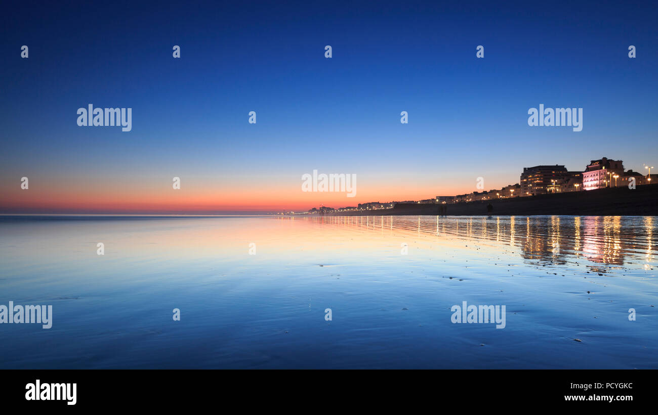 I riflessi del tramonto sulla spiaggia al tramonto, durante la bassa marea a Brighton Foto Stock