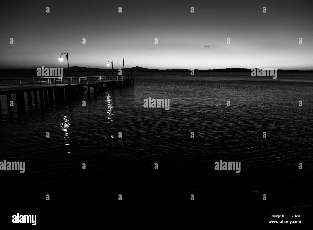 Alcune persone su un molo presso il lago Trasimeno (Umbria, Italia) al tramonto Foto Stock
