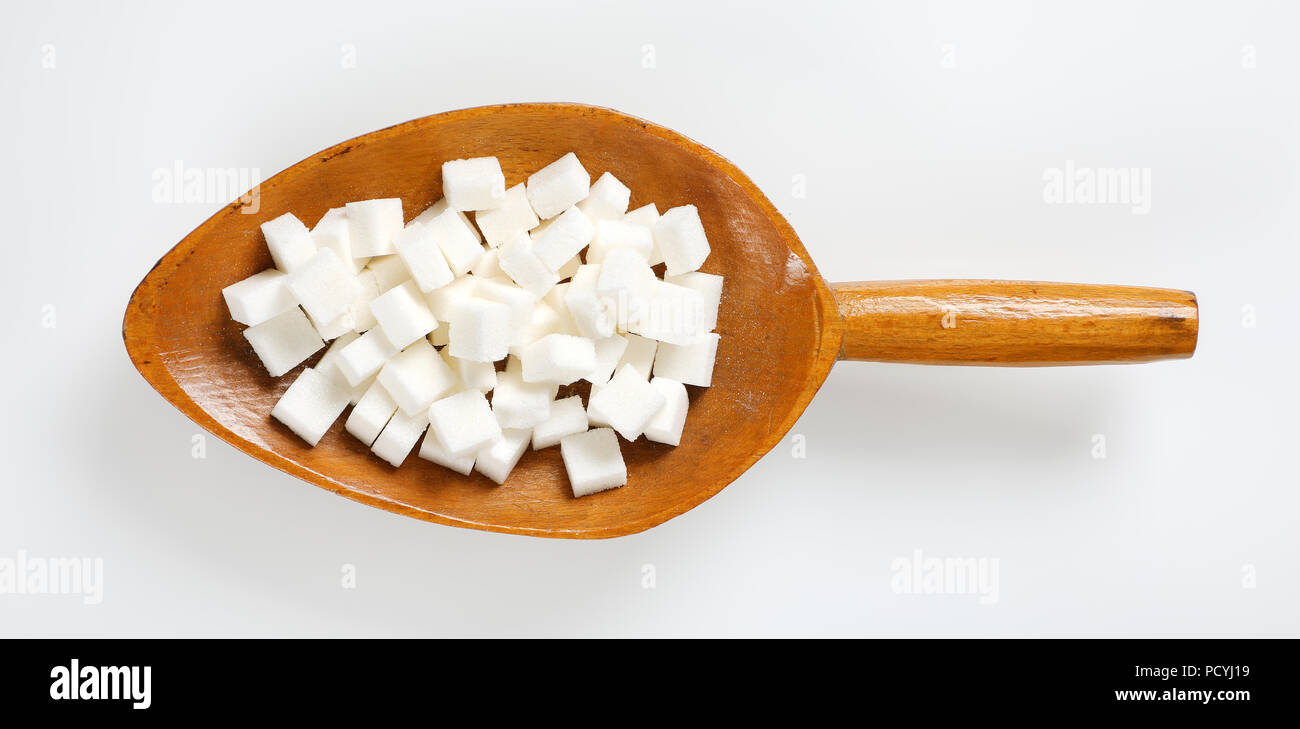 Cucchiaio di zucchero bianco i cubi su sfondo bianco Foto Stock
