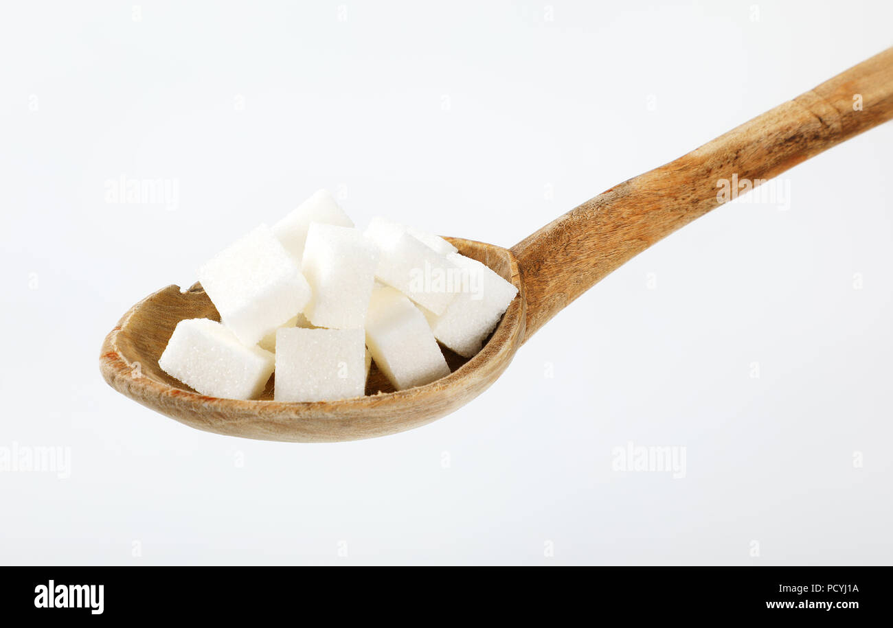 Un cucchiaio di zucchero bianco i cubi su sfondo bianco Foto Stock
