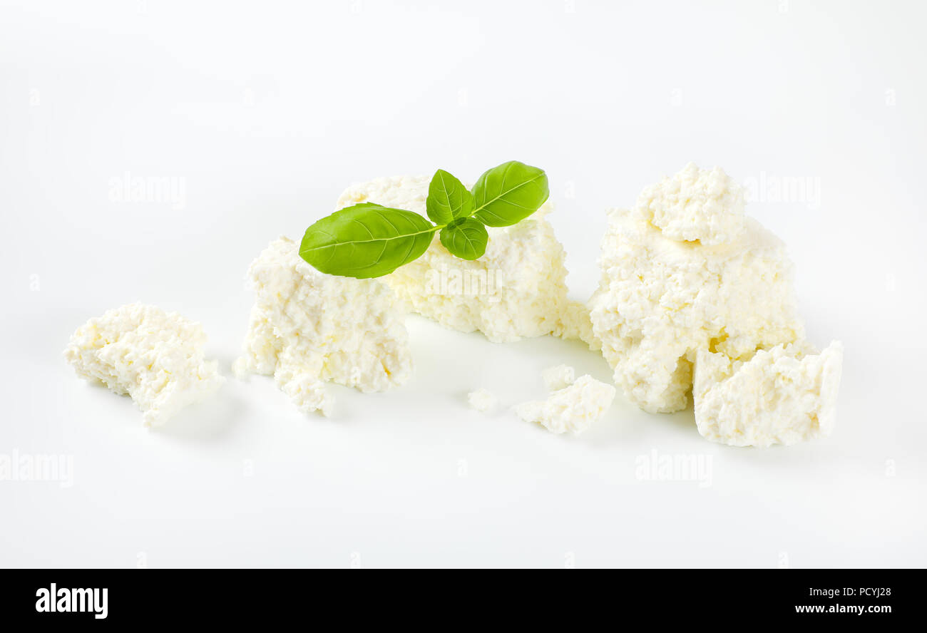 Pezzi di friabile formaggio bianco su sfondo bianco Foto Stock