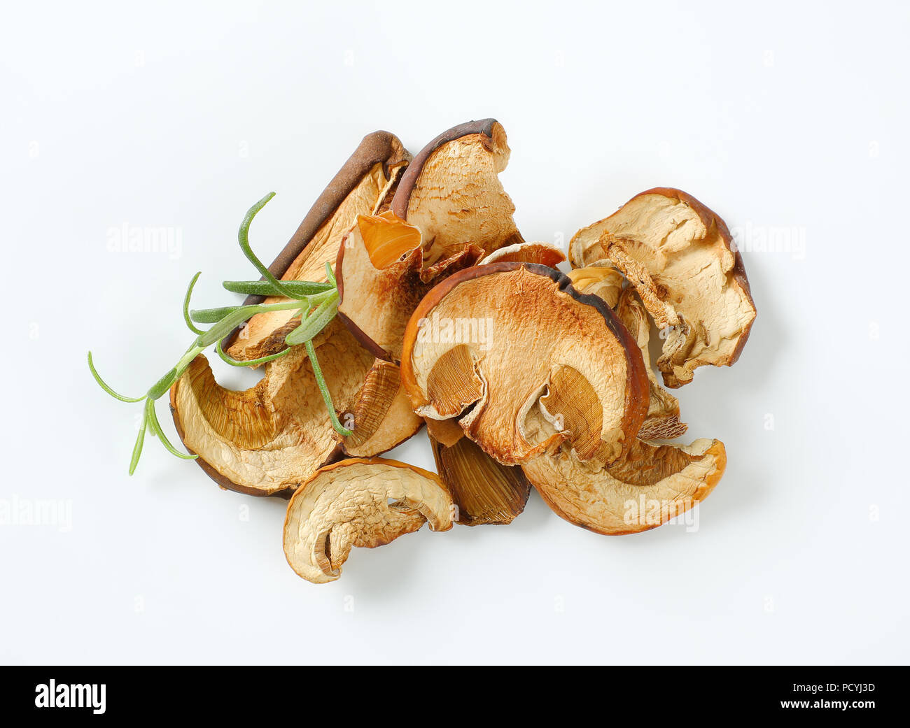 Pugno di funghi secchi e di rosmarino fresco su sfondo bianco Foto Stock