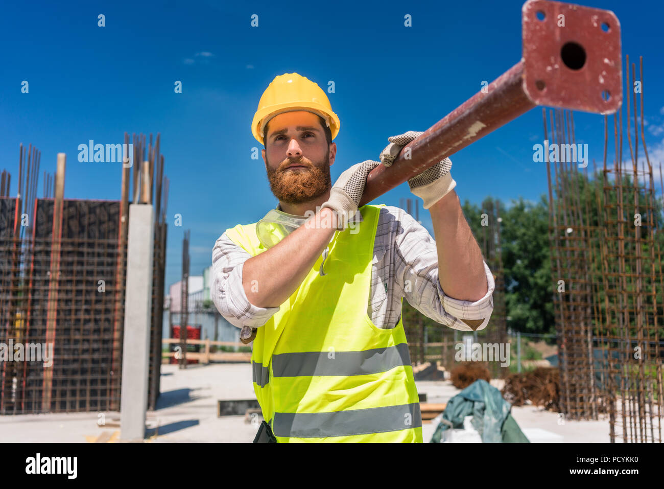 Colletto blu lavoratore portando una pesante barra metallica durante il lavoro Foto Stock