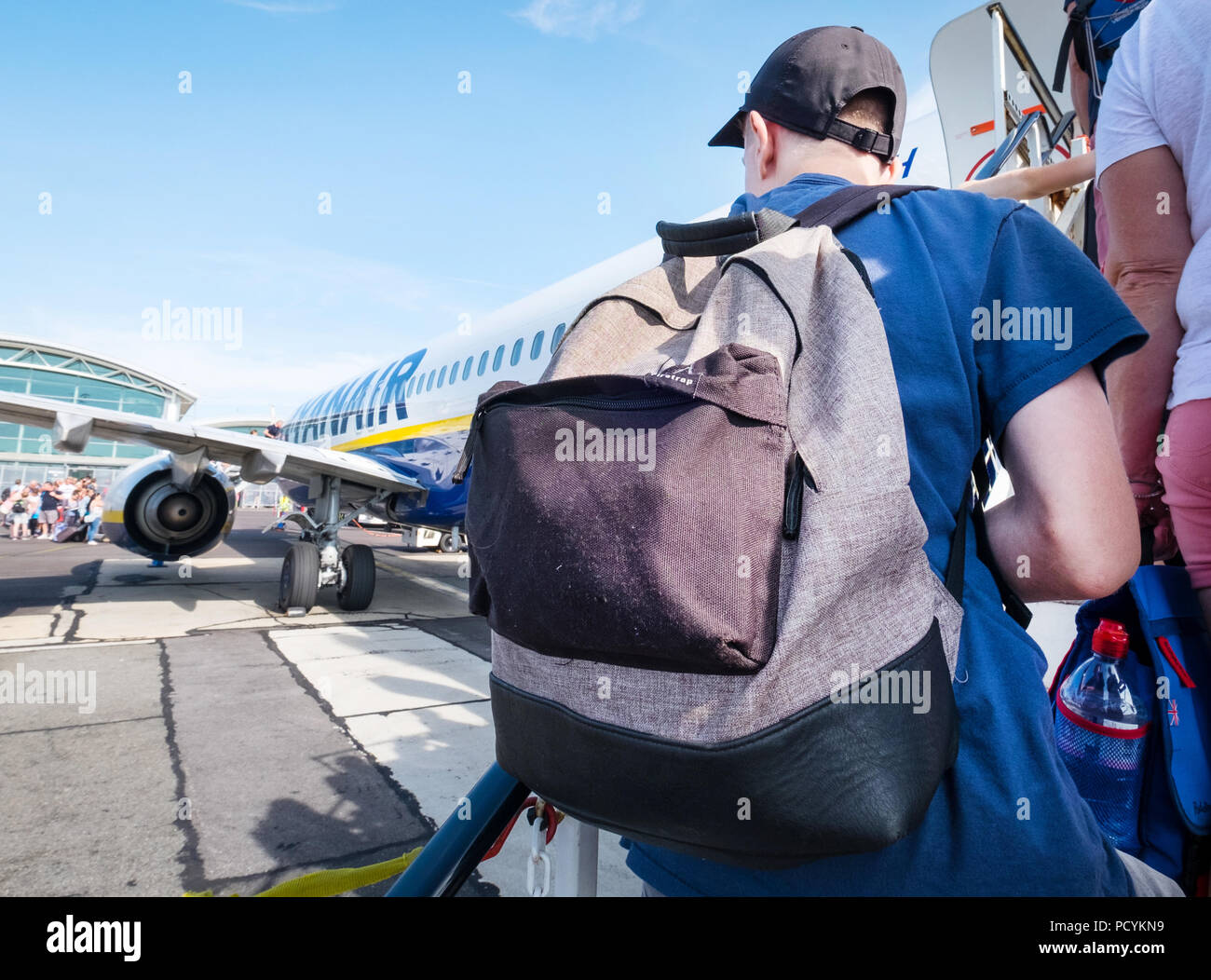 Ryanair passeggero con uno zaino come trasportare il bagaglio a mano di salire a bordo di un aereo Ryanair dopo il pagamento di un supplemento per imbarco prioritario. Foto Stock