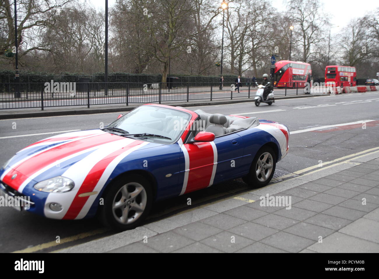 Tipo Cabriolet sport Unione Jack dipinto auto parcheggiate a Park Lane Near Grosvenor House Hotel sulla gelida giornata invernale, con due carrozze a due piani in background Foto Stock