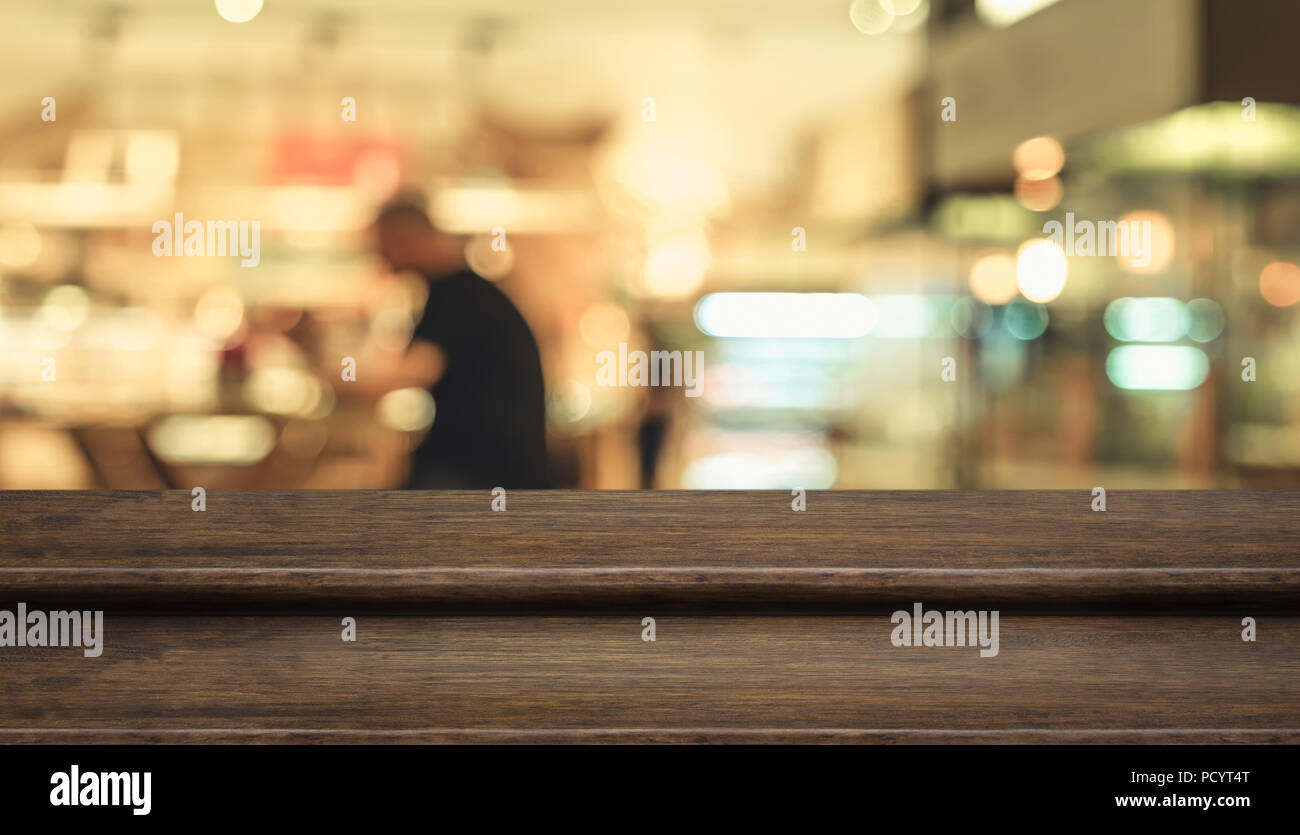 Fase di vuoto legno scuro tavolo ( stand alimentari ) con blur cliente cenare al ristorante cafe sfondo bokeh luce,Mock up per visualizzare o montaggio di pr Foto Stock