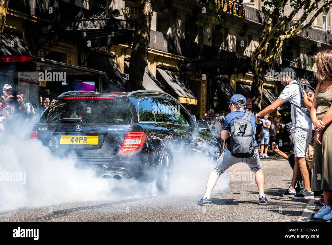 5 agosto 2018 - Londra, Inghilterra. Potente Mercedes AMG C63 Station Wagon bruciando pneumatici a Gumball Rally 3000 evento, mentre auto appassionato di reagire ad esso. Foto Stock