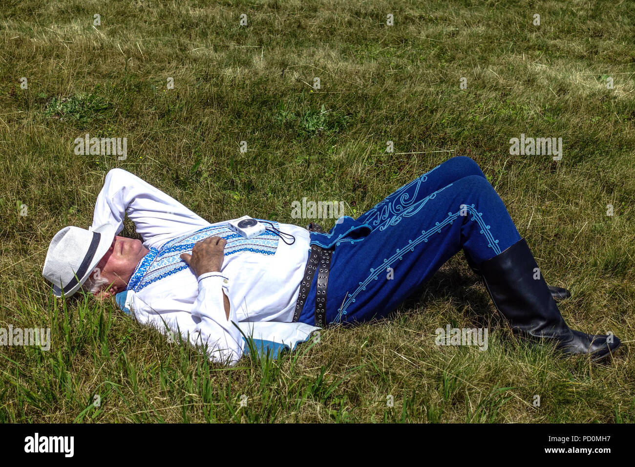 Uomo in costumi folk giacente sul prato, Slovacchia Foto Stock