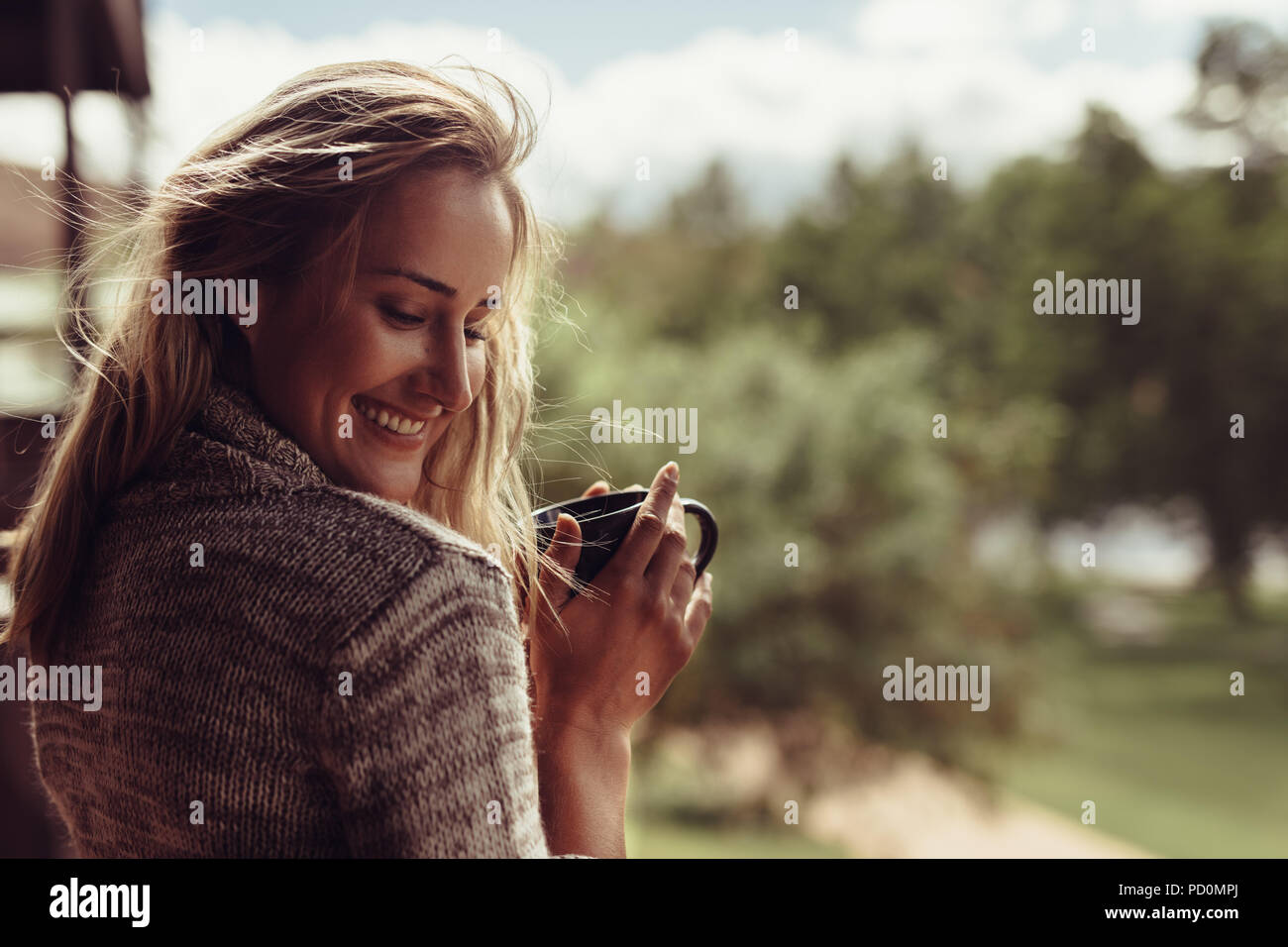 Bella donna sorridente pur avendo il caffè del mattino. Femmina caucasica sentirsi felice in mattinata con una tazza di caffè in mano. Foto Stock