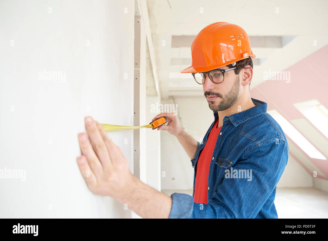 Ritratto di giovane uomo con nastro di misurazione mentre si lavora sul sito in costruzione. Foto Stock