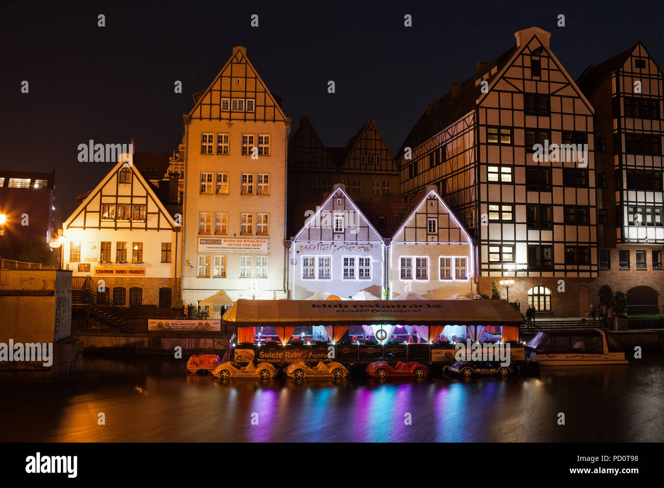 La Polonia, Gdansk, edifici tradizionali sulla Granary Island dal fiume Motlawa illuminata di notte, la città degli angeli discoteca e ristorante Foto Stock