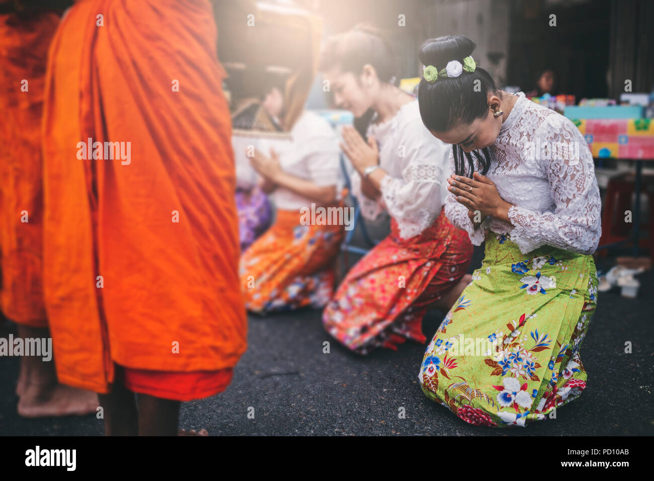 Donna Thai omaggio a un monaco buddista in mattina. Foto Stock